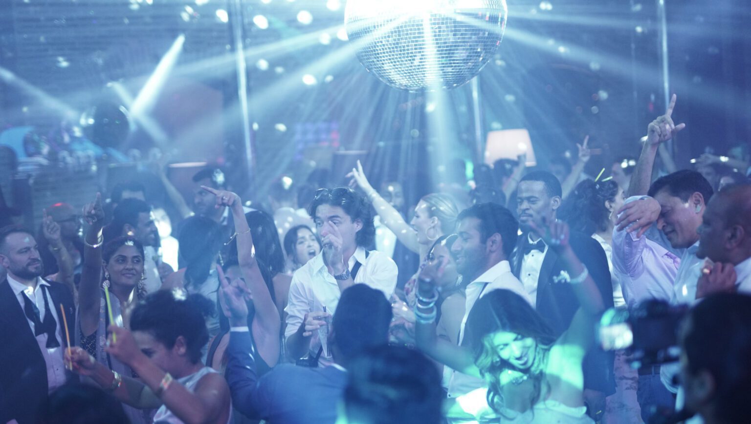 Packed dance floor under a disco ball at a wedding reception