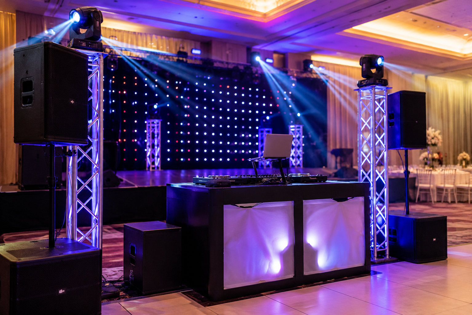 DJ setup with LED backdrop and truss lighting at a wedding reception